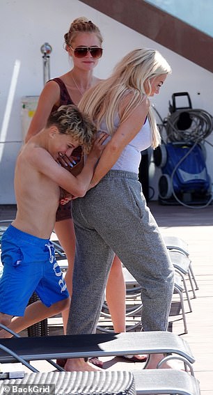Playful: The reality star had been lounging poolside in a skin-tight purple vest top and grey tracksuit bottoms before her kids attempted to get her in the water