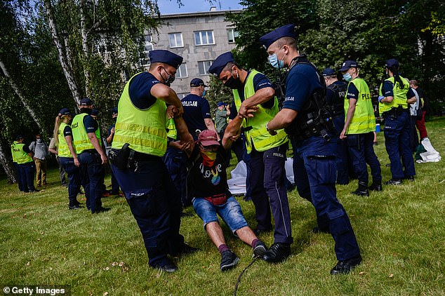 Police remove a protester wearing a shirt saying 